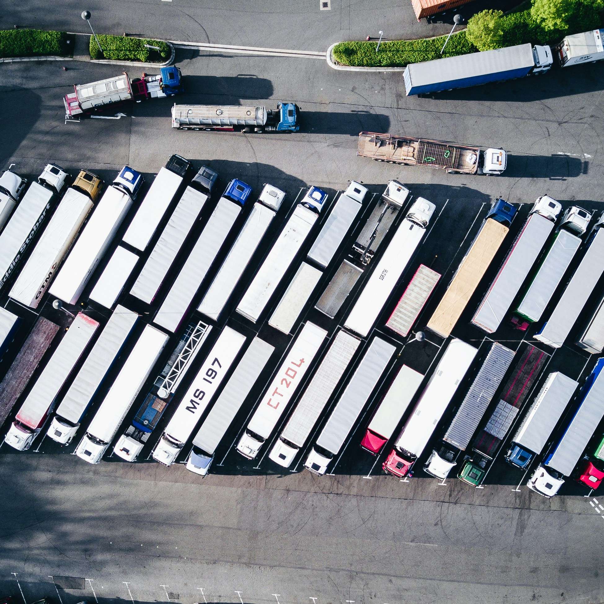 A yard of a manufacturing sites, showing a number of parked lorries.