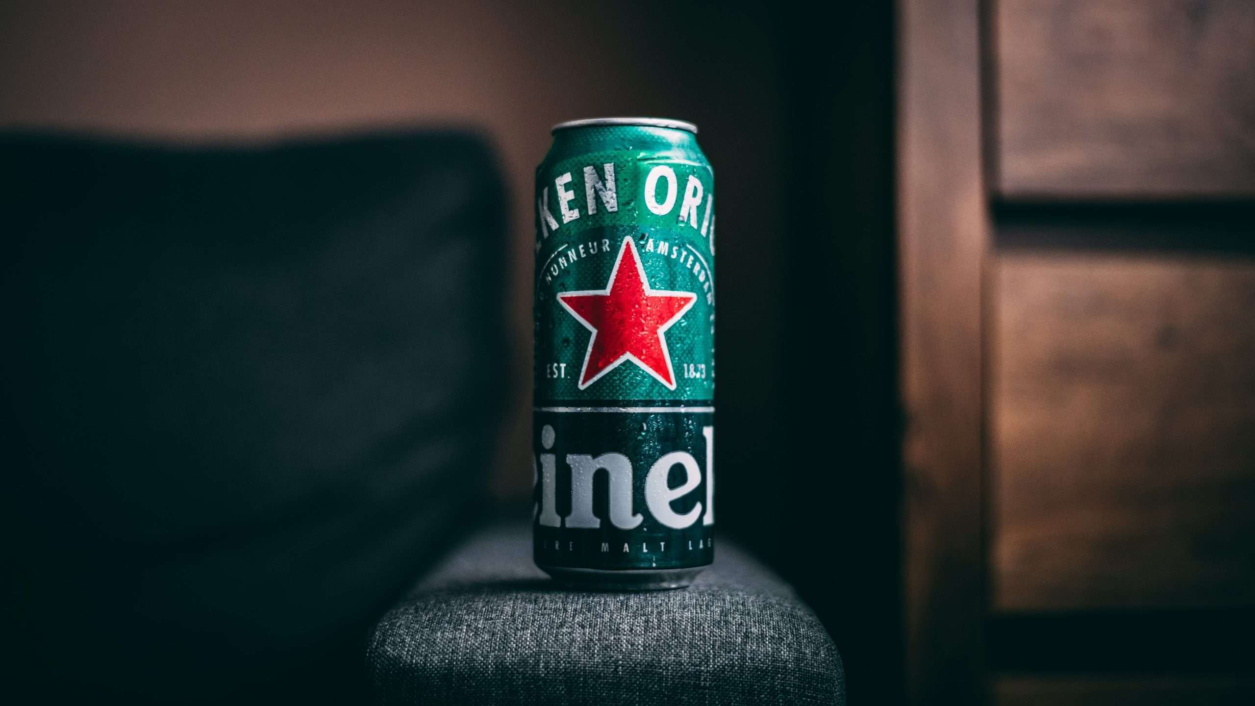 A can of heineken beer sitting on a wooden table.