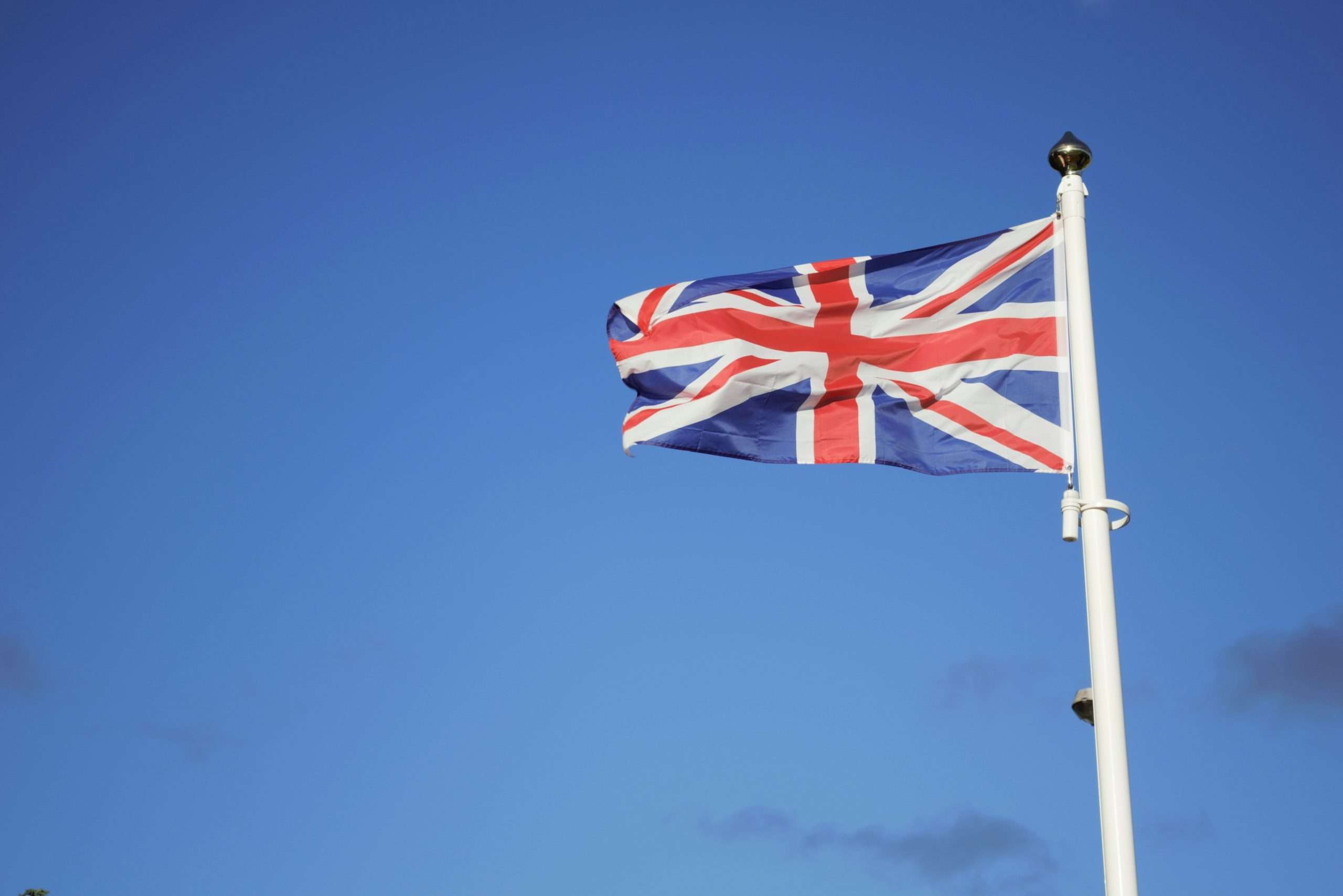 Union jack flag on a pole against blue sky.