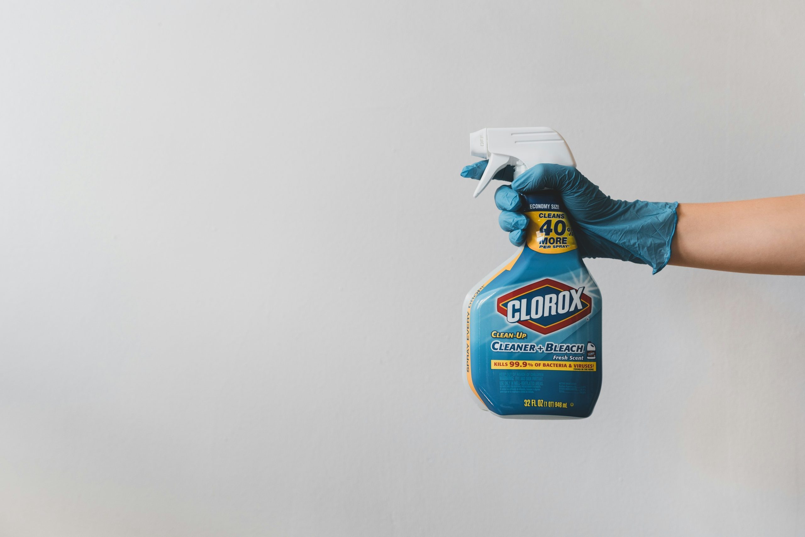 A bottle of clorox spray being sprayed by a blue gloved hand.