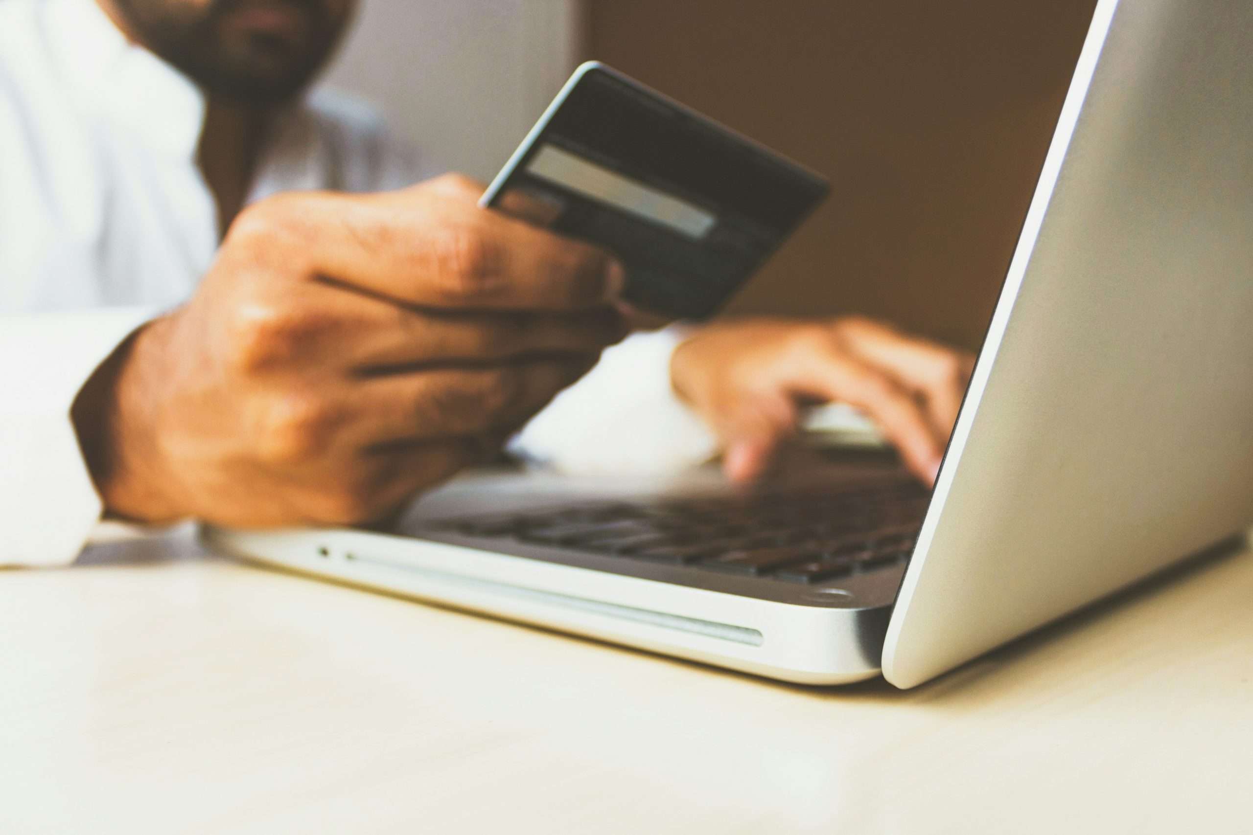 Person with a credit card typing on a laptop.