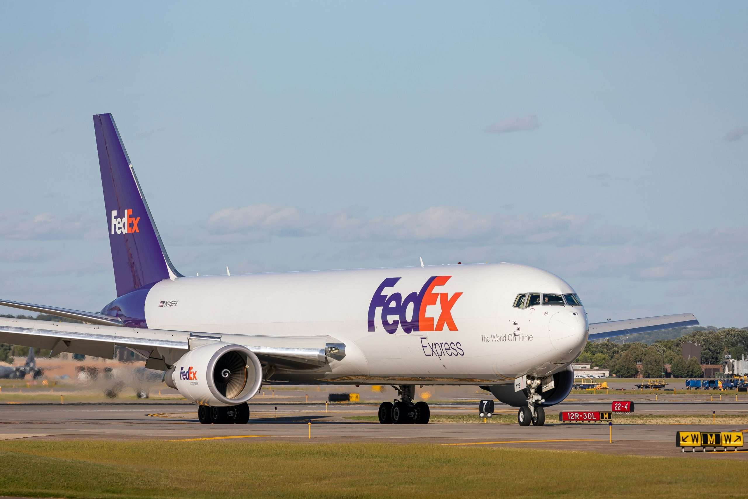 A fedex branded plane sitting in an airport.