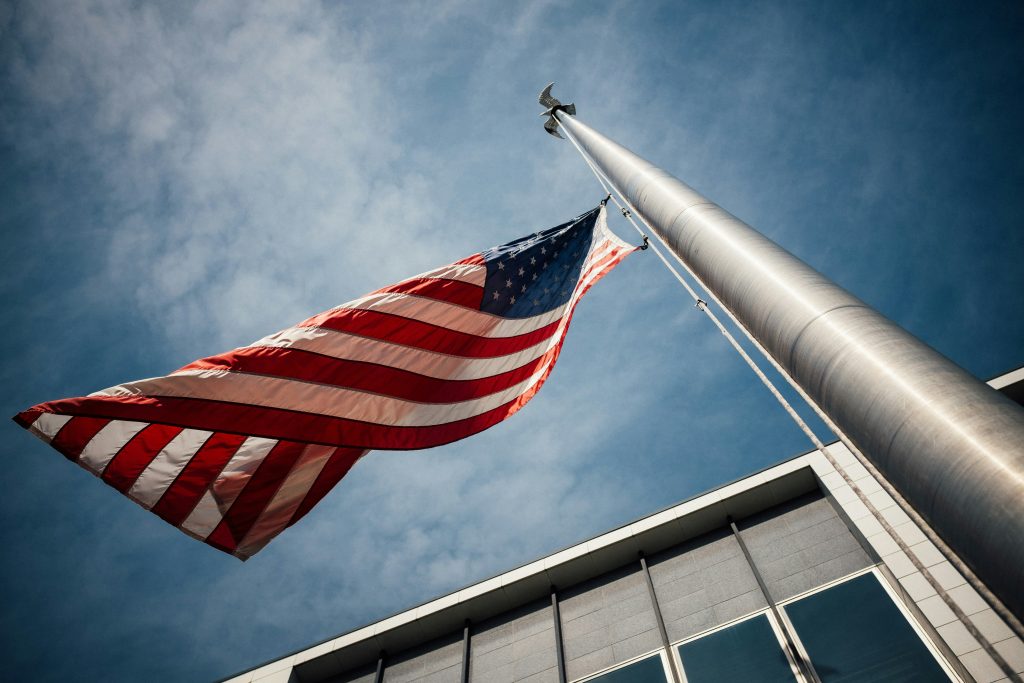 An image of the USA flag flying next to a government building.