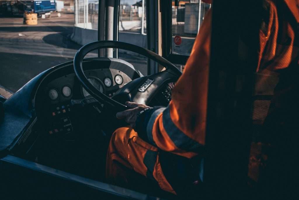 A factory wearing an orange uniform, driving a forklift.