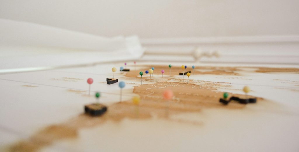 An image of a series of pins placed against a geographical map to reflect supply chain mapping.