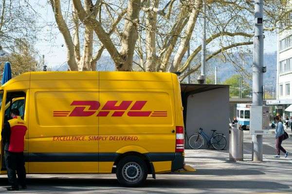 A DHL van unloading deliveries on a street.