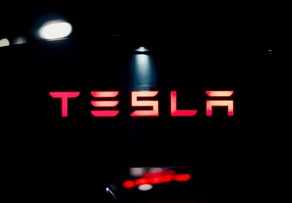 The Tesla brand lit up in red on a black background.