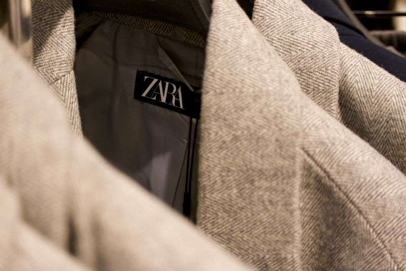 A rail of tan woolen Zara coats in a shopping store.