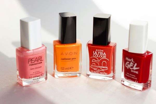 A row of nail polishes including an Avon bottle.