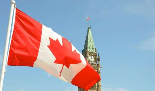 A Canadian flag flying against a government building.