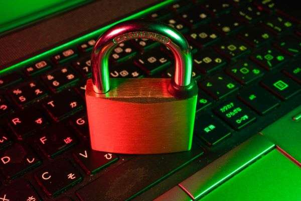 A laptop seen close up with a padlock sitting on top, representing cybersecurity.