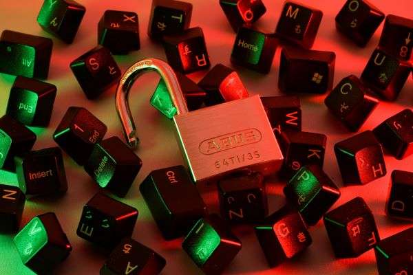 A padlock sitting among a set of keys from a laptop representing the concept of cybersecurity.