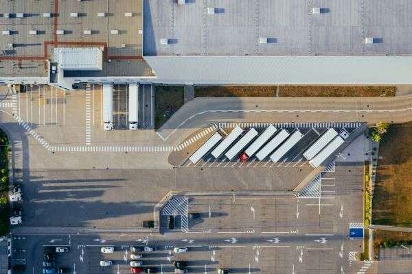 A number of lorries from a logistics provider parked outside a factory.