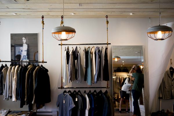A boutique retail store carrying clothes neatly displayed between two lights.