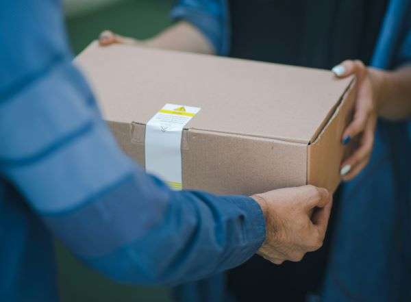 An image of a package being handed from person delivery driver.