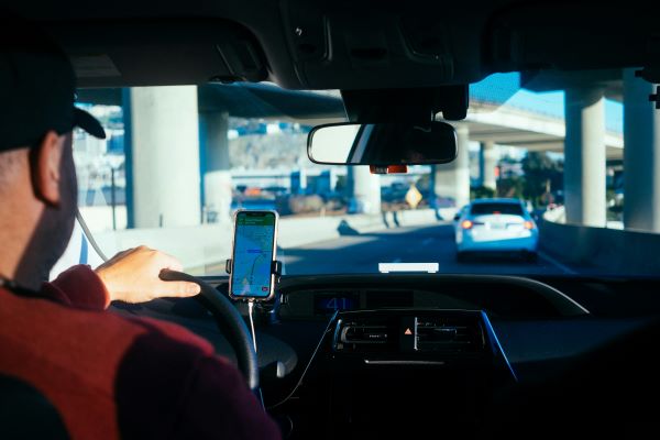 A truck driver in the vehicle cab, viewing a map on a smartphone.