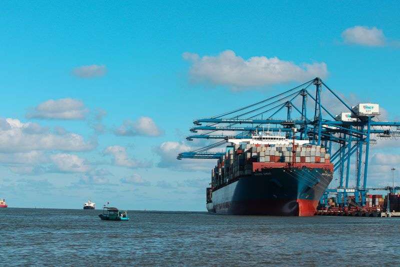 A cargo ship stopping at a port to load containers. South Africa have recently committed to solving backlogged ports within the year.