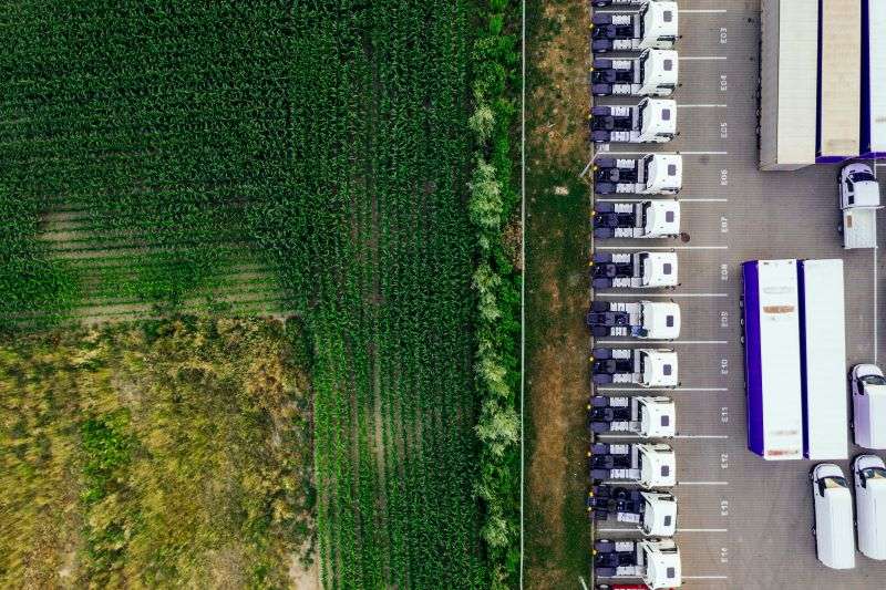 A queue of lorries parked in a warehouse lot awaiting trailers.