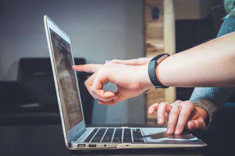 Several people pointing to data on a laptop in business context.