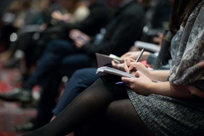 Several stakeholders taking notes during a formal business meeting.