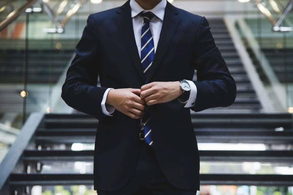 An executive buttoning their jacket preparing for a job interview as part of recruitment process.