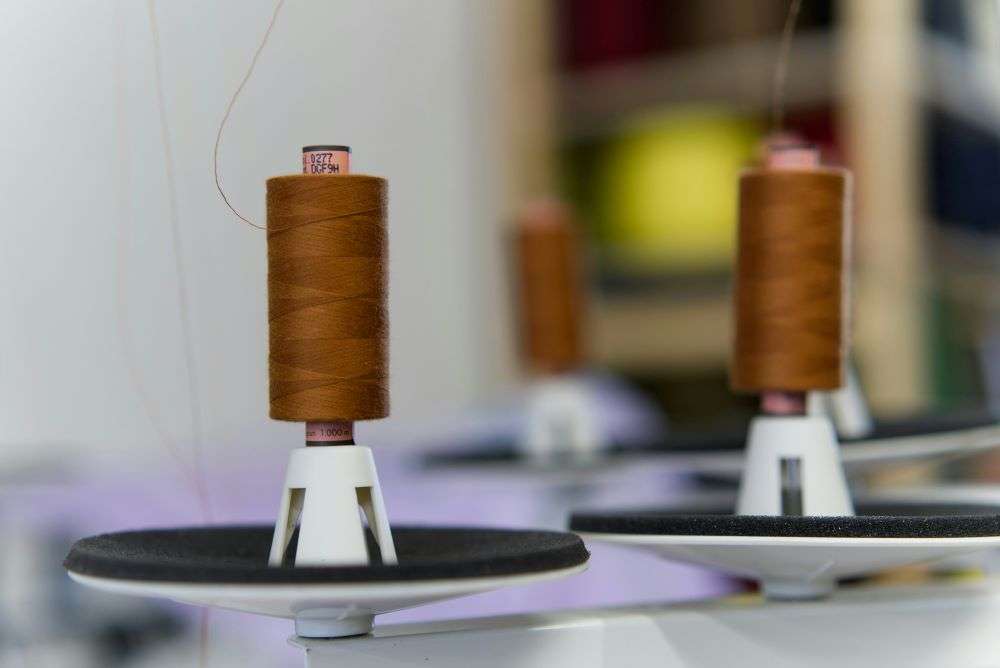 Spools of brown thread on a sewing machine. The Fashion Industry Benchmarking Study reveals that managing forced labor risks and navigating an uncertain U.S. economy are the primary concerns for fashion executives this year.