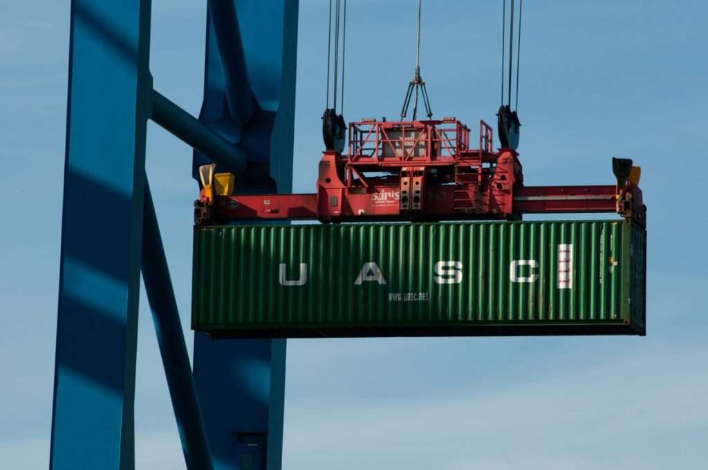 A shipping container on a crane at port. Port of Oakland and Northwest Seaport Alliance join FLOW to boost supply chain efficiency.